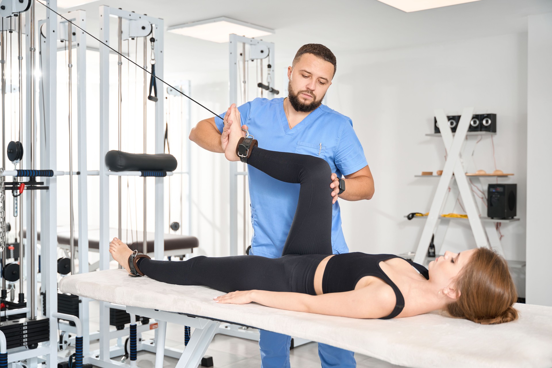 Experienced physiotherapist uses special exercise machine to work with patient